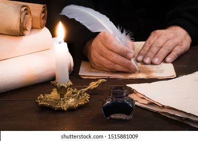 A lighted candle against the background of blurred scrolls of parchment, books and bird's feather