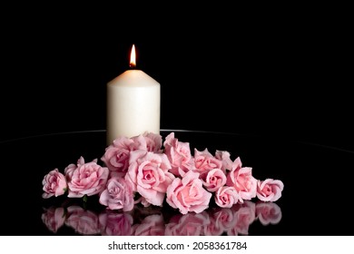LIGHTED CANDLE AND ELEGANT PINK ROSES ARRANGEMENT ON DARK BACKGROUND. ALL SOULS DAY, DEATH, DECEASE, PRAYER, MEMORIAL DAY, DUEL, MOURNING, GRAVE, CEMETERY, BURIAL AND FUNERAL CONCEPT.