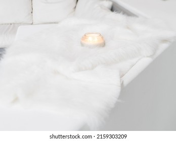 Lighted Candle On A White Fur Blanket