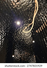 Lighted ceiling with a reflection of a persons head. The reflection is blurry and the persons head is not visible