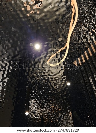 Lighted ceiling with a reflection of a persons head. The reflection is blurry and the persons head is not visible