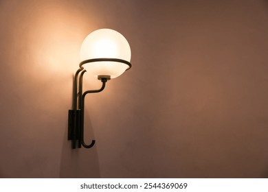 A lighted glass globe hanging from a wall. The light is on and the globe is white - Powered by Shutterstock