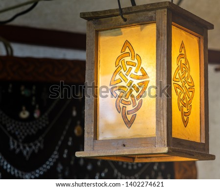 Lighted lantern with an abstract pattern resembling a rune, wooden frame with yellow glass, craft