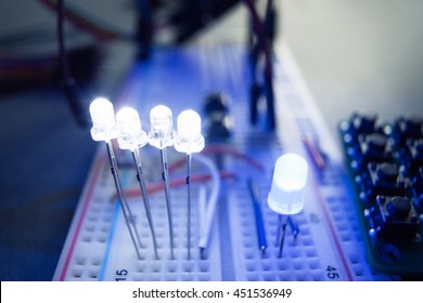 Light-emitting diodes on breadboard electrical panel. Close-up of blue led, shining on engineer workplace. Electrician-inventor laboratory