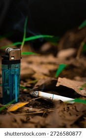 A lighter and a single cigarette placed side by side on a flat surface. The lighter is used to ignite the cigarette.