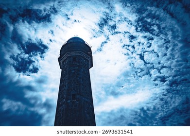 a lighthouse against the light with clouds
