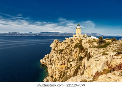 Lighthouse At Cape Ireon In Greece, Europe, On Clear Sunny Day. Wide-angle Epic Scene Of Rocky Cape With Stone Lighthose On Top.