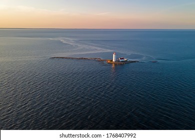 The lighthouse, consisting of a main tower and cabin located on a stone ridge on the island in the middle of the Bay, away from the shores at sunset. Background, texture, Wallpaper, photo from air
