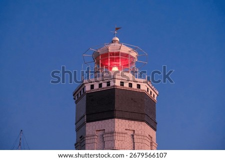 Lighthouse with glowing red light tower against deep blue evening sky in Anapa, Russia