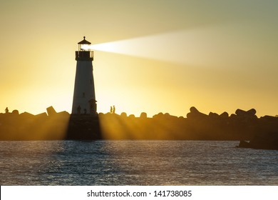 Lighthouse with light beam at sunset