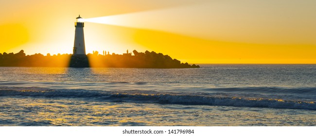 Lighthouse With Light Beam At Sunset