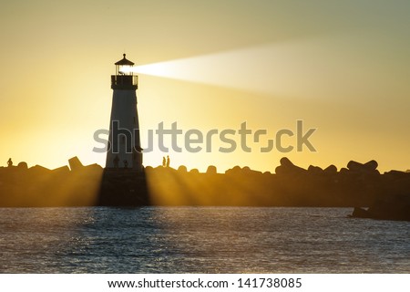 Lighthouse with light beam at sunset
