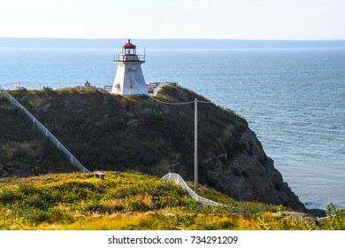 The lighthouse on Cape Enrage, New Brunswick, Canada, on the edge of the rocky angled cliff with fencing and poles at angles