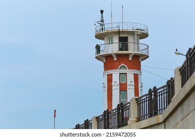 Lighthouse On The Embankment Against The Blue Sky Without Clouds. Border Guard Silhouette. Blagoveshchensk, Russia. State Border With China. Selective Focus. Blurred Foreground.