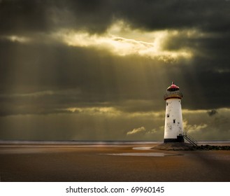 Lighthouse On North Wales Coast Illuminated In The Golden Afterglow Of A Storm At Sea