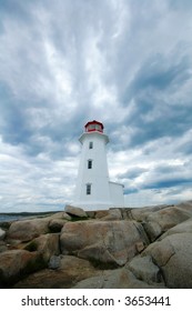 Lighthouse on a rocky beach with white clouds.