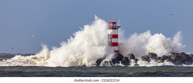 Lighthouse on the south pier in IJmuiden, Netherlands, being struck by big breaking waves caused by the storm Dudley in february 2022 - Powered by Shutterstock