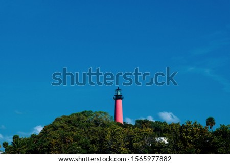 Lighthouse peers over lush beachfront foliage