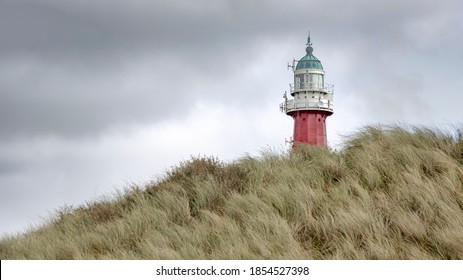 The lighthouse of Scheveningen near the city of the Hague in the Netherlands. The foreground shows a sand dune full of grass and the sky is overcast.
