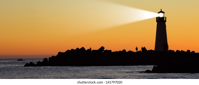 Lighthouse With Searchlight Beam At Sunset