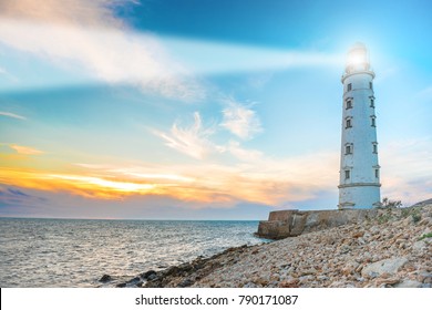 Lighthouse searchlight beam through sea air at night. Seascape at sunset