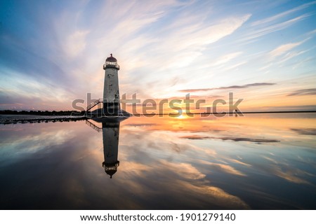 Lighthouse standing in pool of water stunning sunset sunrise reflection reflected in water and sea steps up to building north Wales seashore sand beach still water orange glow golden hour blue hour