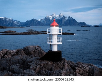 The lighthouse stands proudly against snowcapped mountains, creating a stunning view - Powered by Shutterstock