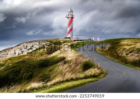 Lighthouse at the top of a winding road on rocky shores overlooking the Atlantic Ocean at Heart's Content Newfoundland Canada.