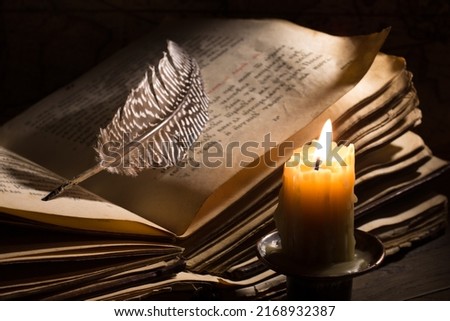 Lighting candle near a medieval book. Vintage still life with open old book.