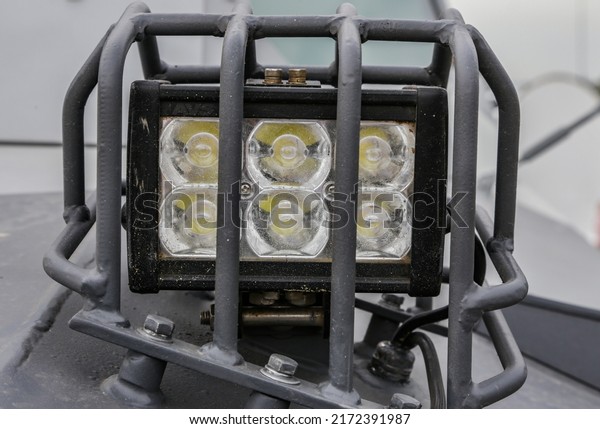 Lighting equipment for moving vehicles. LED\
illuminator on military equipment close-up.Headlight with\
protection on an armored\
car.