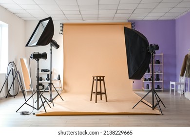 Lighting equipment, stool and beige cyclorama in modern photo studio - Shutterstock ID 2138229665