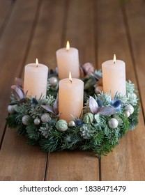 Lighting four candles on the advent wreath on Christmas day. Advent wreath on the wooden dining table in the festive season in December.