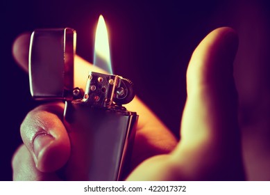 Освещение вверх Зажигалка крупным планом Фото. Прохладный металлический зажигалка в руке.