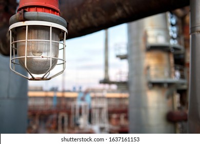 Lighting mast with lantern in explosion-proof and fire-proof design close-up over background of pipelines buildings and equipment of chemical plant with copy space