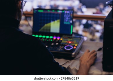Lighting technician operator working on mixing console, workplace during live event, stage concert show broadcast, light mixer controller panel, sound technician with professional equipment at venue
