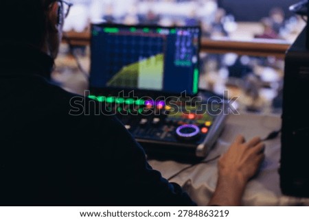 Lighting technician operator working on mixing console, workplace during live event, stage concert show broadcast, light mixer controller panel, sound technician with professional equipment at venue
