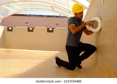 Lighting Technician Working On The Refurbishment Of An Empty Swimming Pool