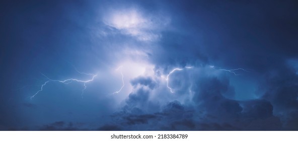 Lightning in the blue sky with clouds at night. - Powered by Shutterstock