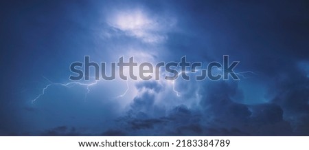Lightning in the blue sky with clouds at night.