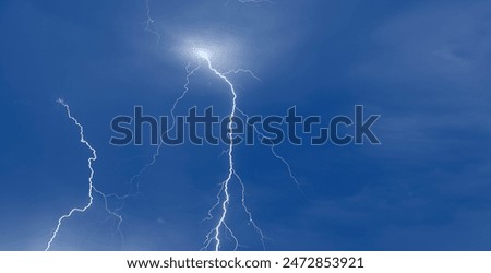 Lightning in the blue sky with clouds at night.