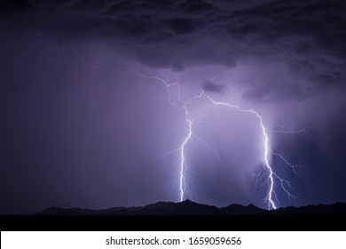 Lightning bolt strike from a storm over a mountain at night - Shutterstock ID 1659059656