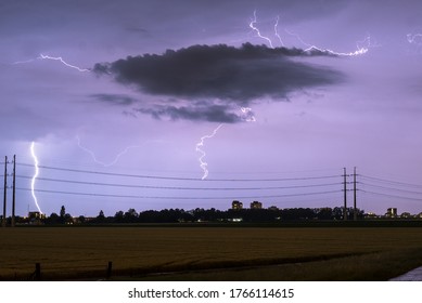 Lightning Bolts Strike Down Near Power Lines During A Stormy Night