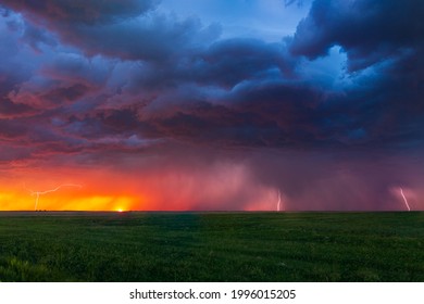 Lightning bolts strike at sunset along the Wyoming and Colorado border. The last remnants of the sun can be seen setting along the horizon with color hues of pinks, purples, reds, and oranges. - Powered by Shutterstock