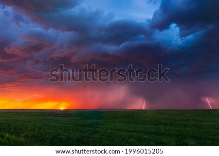 Lightning bolts strike at sunset along the Wyoming and Colorado border. The last remnants of the sun can be seen setting along the horizon with color hues of pinks, purples, reds, and oranges.