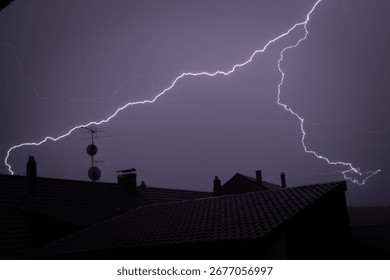 lightning flash on rooftops on an evening sky 