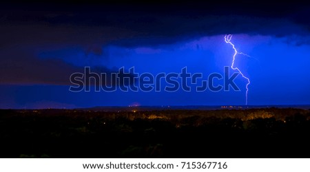 Lightning on the background of the night sky and a stormy cloud over the city.