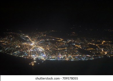 Lights of night Sochi city near sea coast photographed from flying airplane