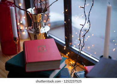 lights lights on the background of the window with candlesticks standing on the books on the windowsill