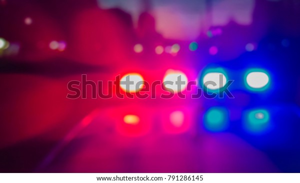 Lights of police car in\
night time. Night patrolling the city, lights flashing. Abstract\
blurry image.