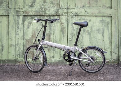 lightweight folding bike in an alley against a grunge wooden fence